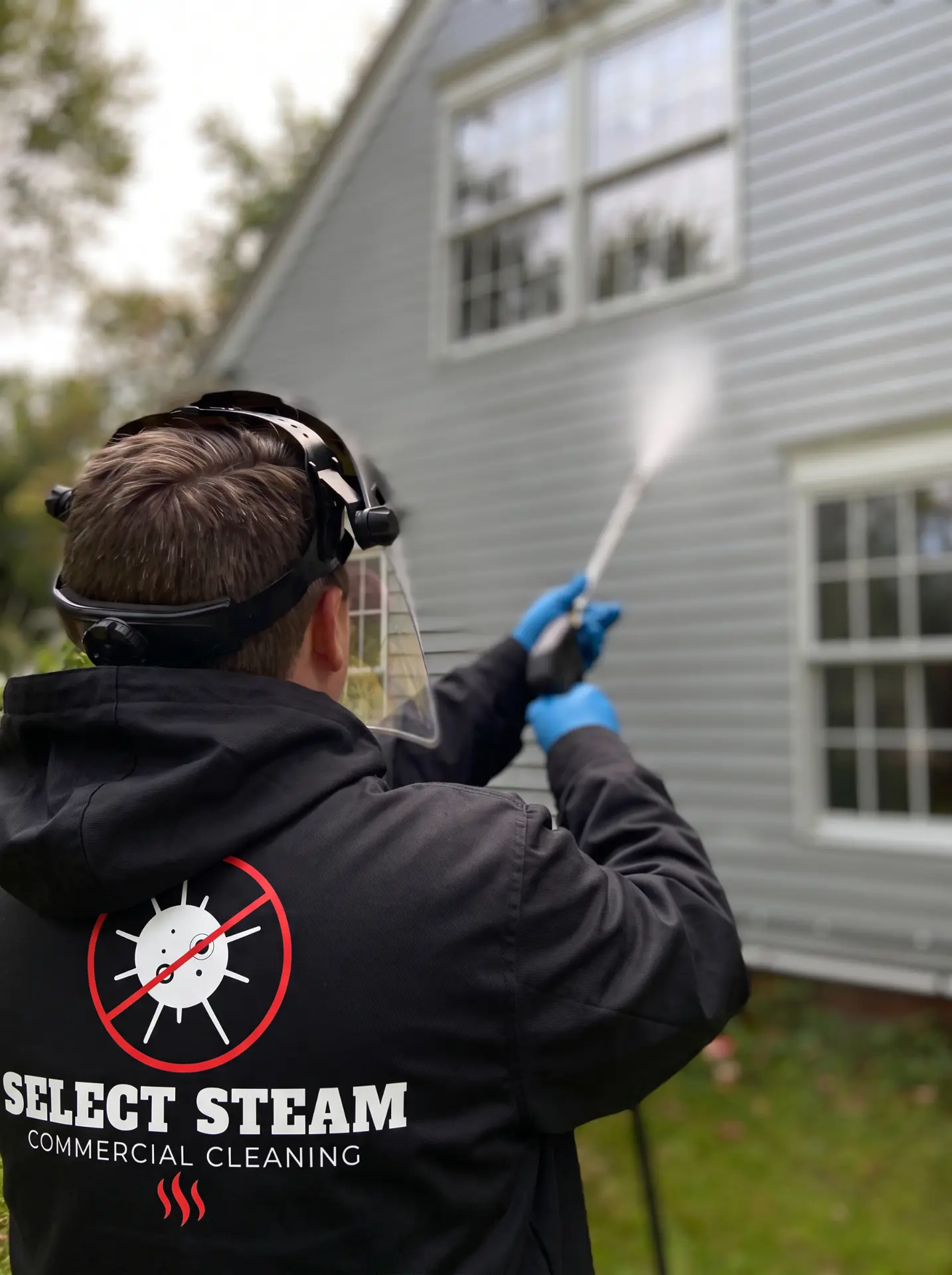 Select Steam technician in branded uniform pressure washing house siding