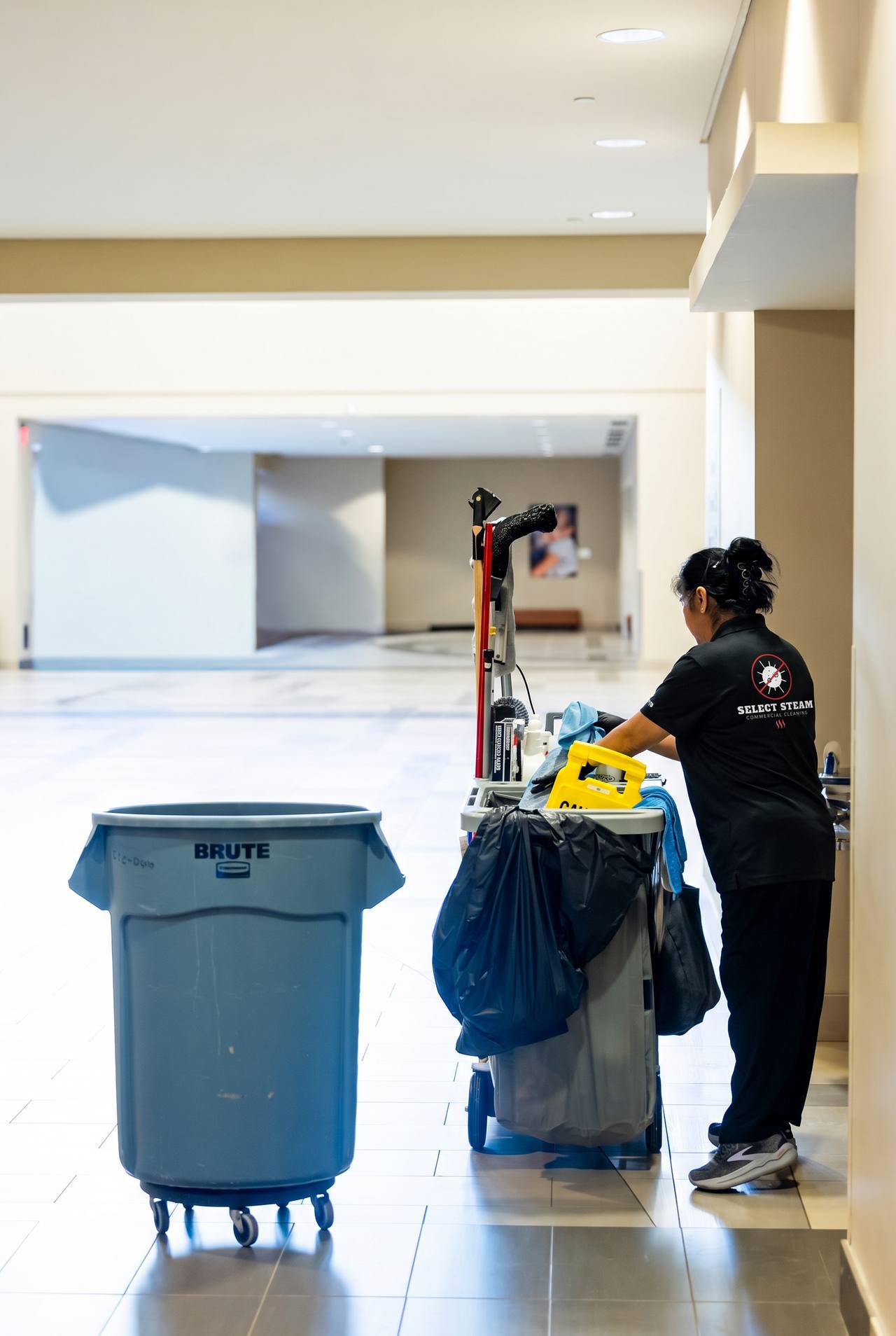 Commercial cleaner moving a janitorial cart through a facility