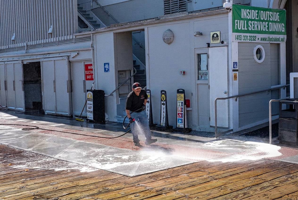 Worker pressure washing a commercial sidewalk